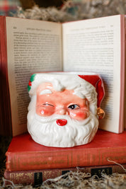 Handcrafted Santa Claus candle resting on vintage books