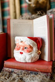 Handcrafted Santa Claus candle resting on vintage books