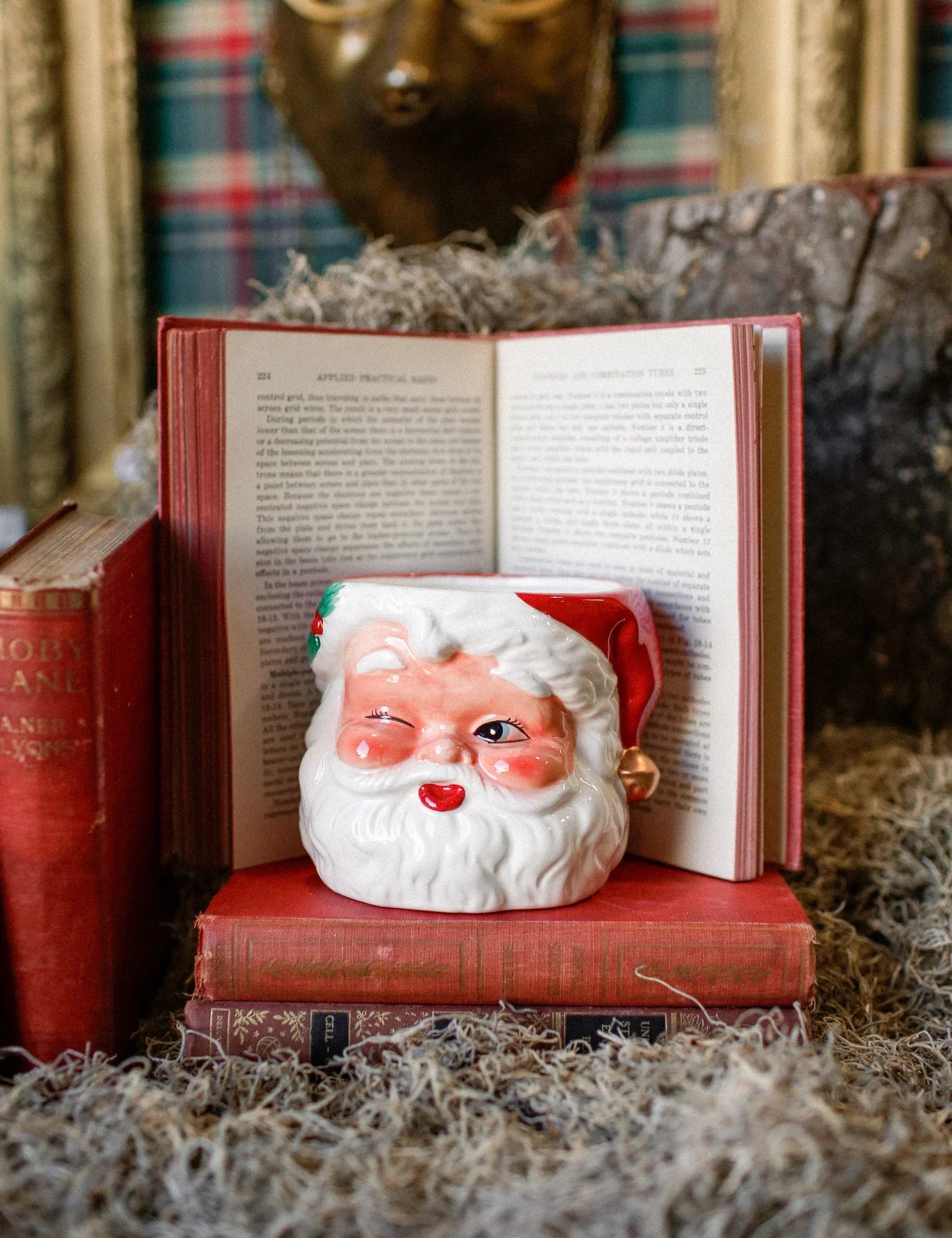Handcrafted Santa Claus candle resting on vintage books