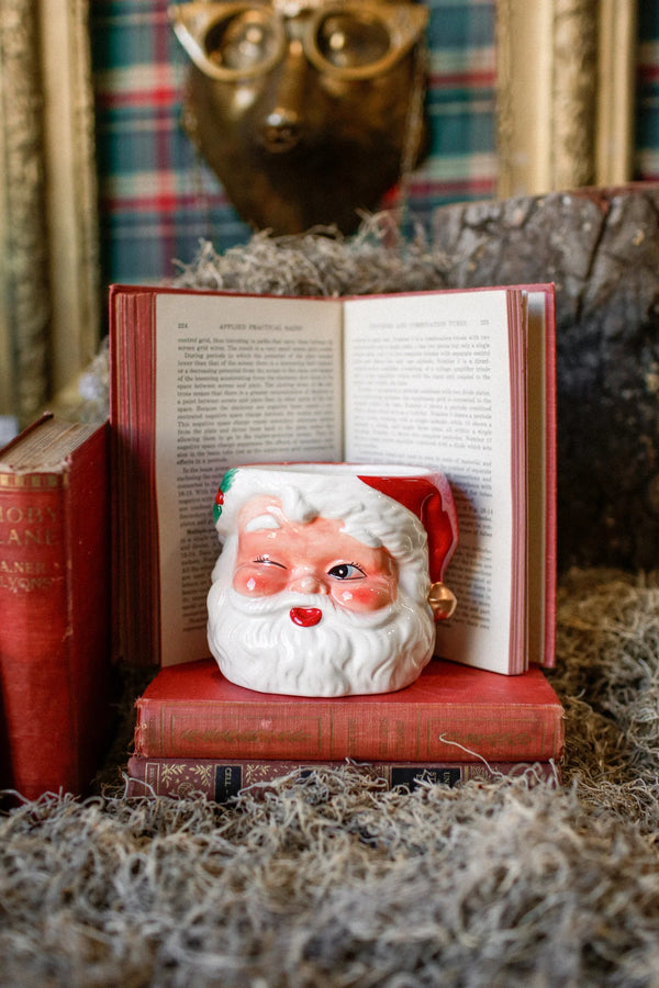 Handcrafted Santa Claus candle resting on vintage books